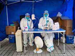 TOPSHOT - Les agents de santé attendent que les gens scannent un code de santé pour tester le coronavirus Covid-19 dans le district de Jing'an à Shanghai le 22 décembre 2022.