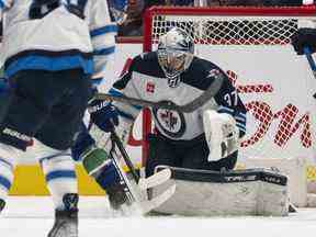 Le gardien de but Connor Hellebuyck des Jets de Winnipeg effectue un arrêt contre les Canucks de Vancouver lors de la première période de l'action de la LNH le 17 décembre 2022 au Rogers Arena de Vancouver, Colombie-Britannique, Canada.