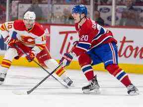 Juraj Slafkovsky des Canadiens tentera de faire une passe devant Jonathan Huberdeau des Flames en troisième période lundi soir au Centre Bell.