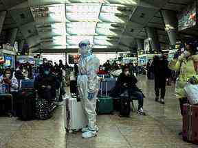 Un passager portant un équipement de protection est vu dans une gare de Pékin le 28 décembre 2022. (Photo par Noel CELIS / AFP)