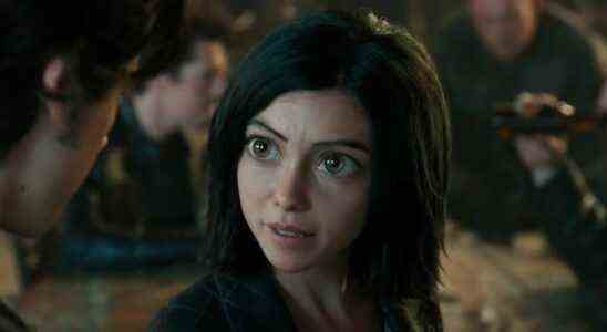 Alita looks up at Hugo while speaking in a bar in Alita: Battle Angel.