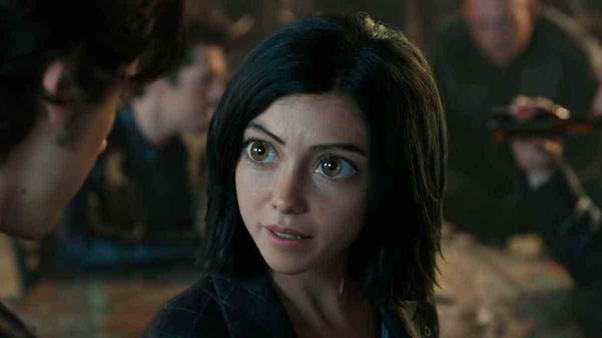 Alita looks up at Hugo while speaking in a bar in Alita: Battle Angel. 