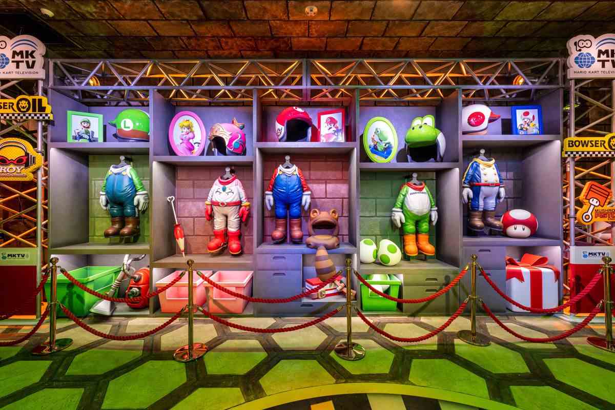 Une photo du manège Mario Kart de Super Nintendo World, qui montre les tenues et le casque de karting de Mario, Luigi, Peach, Yoshi et Toad.