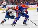 L'attaquant des Oilers d'Edmonton Connor McDavid (97) protège la rondelle contre l'attaquant de l'Avalanche du Colorado Alex Newhook (18) au cours de la deuxième période à Rogers Place. 