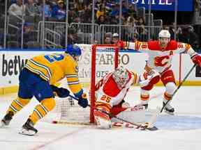 Le gardien des Flames de Calgary Jacob Markstrom et l'attaquant Elias Lindholm défendent le filet contre l'attaquant des Blues de St. Louis Noel Acciari au Enterprise Center de St. Louis le mardi 10 janvier 2023.