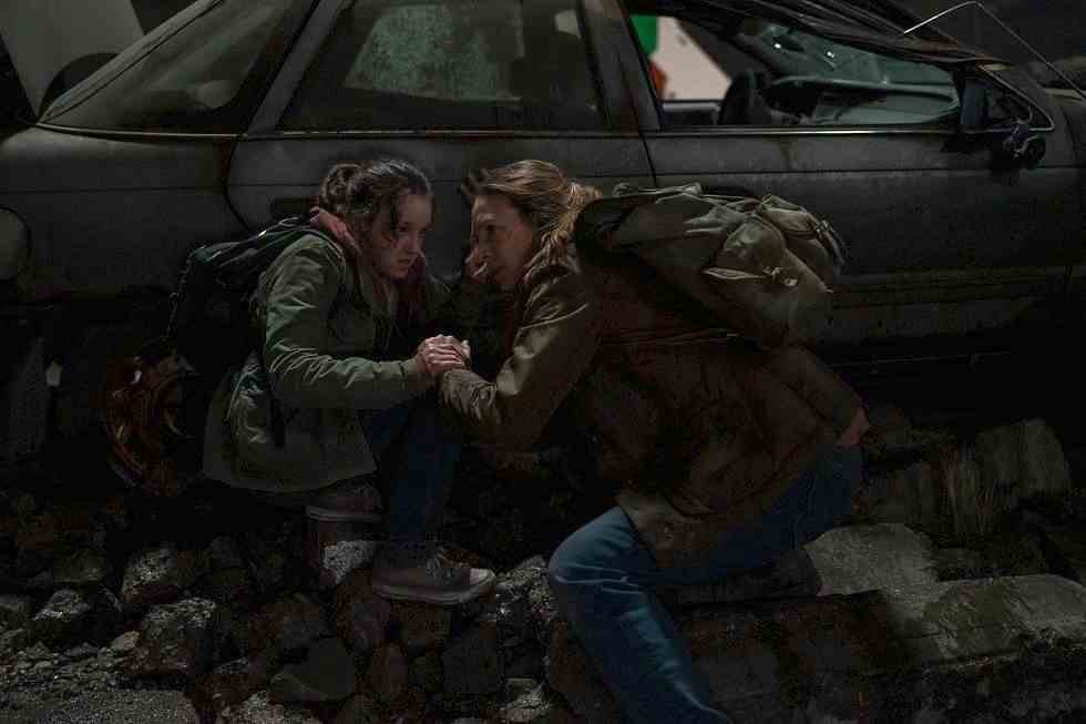 Ellie (Bella Ramsey) et Tess (Anna Torv) accroupies derrière une voiture délabrée dans une image de The Last of Us