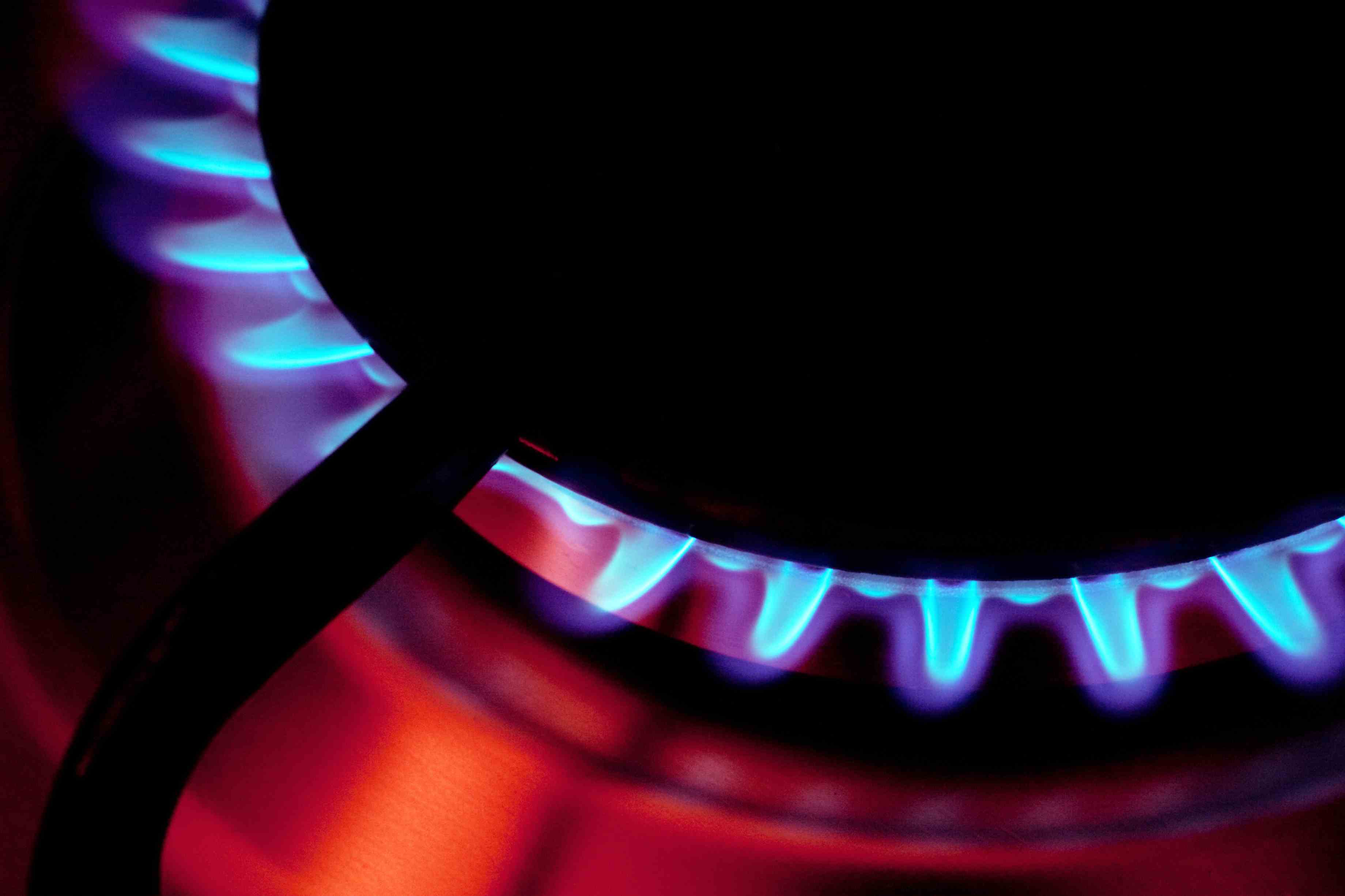 Des flammes bleues brûlent sur une cuisinière à gaz.