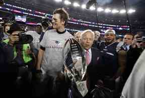 Le propriétaire des Patriots de la Nouvelle-Angleterre, Robert Kraft, au centre, porte le trophée avec le quart-arrière de son équipe, Tom Brady, alors qu'ils quittent le terrain après le match de championnat de l'AFC 2018.