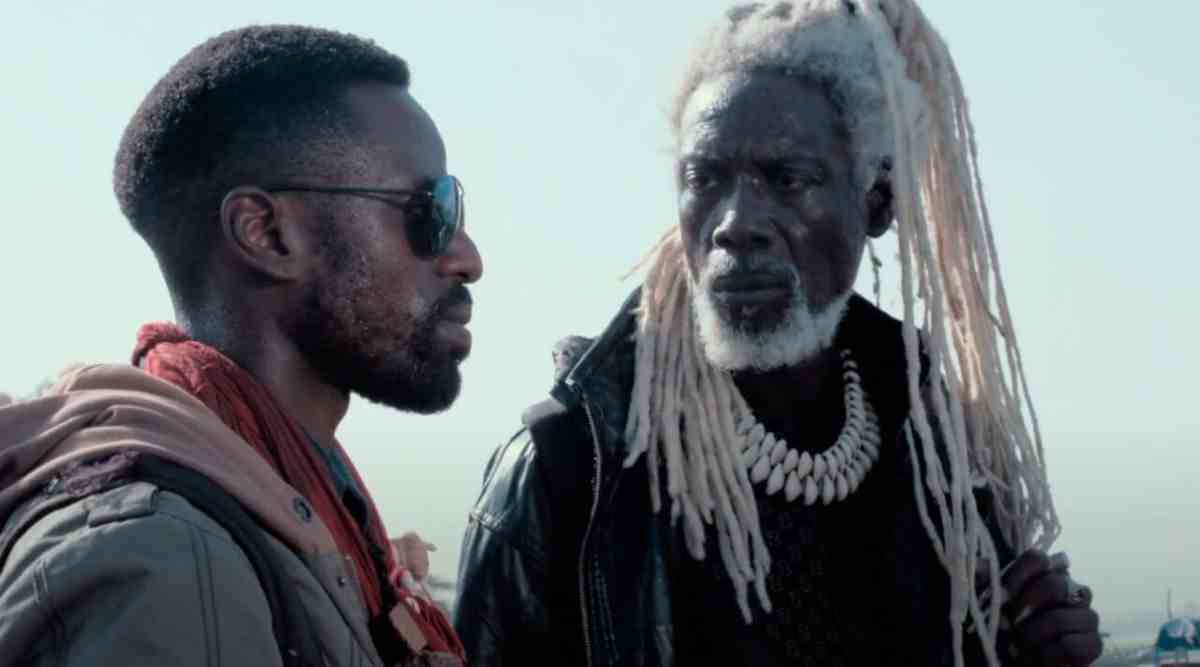 Yann Gaël et Mentor Ba au Saloum.  Gael regarde droit devant lui avec des lunettes de soleil foncées, tandis que Ba regarde Gael.