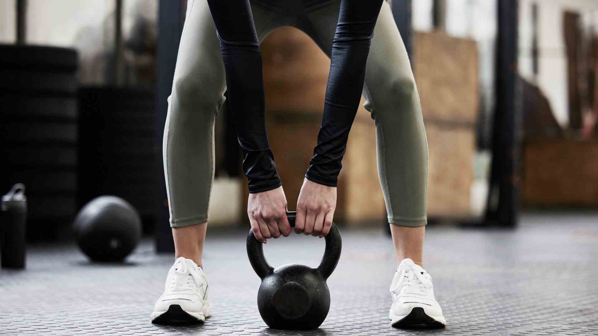 Personne se penchant pour se pencher sur la rangée tenant un kettlebell entre ses jambes