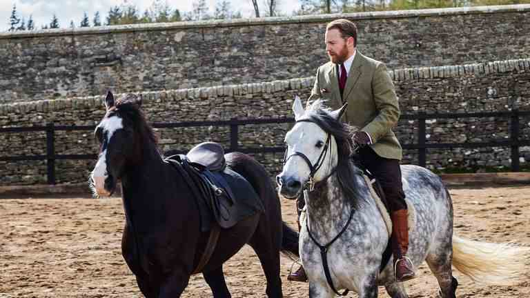 Siegfried dans All Creatures Great &  Petit monte un cheval blanc à côté d'un noir.