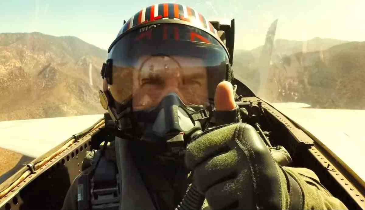 Tom Cruise in flight gear giving the camera a thumbs up from a fighter cockpit