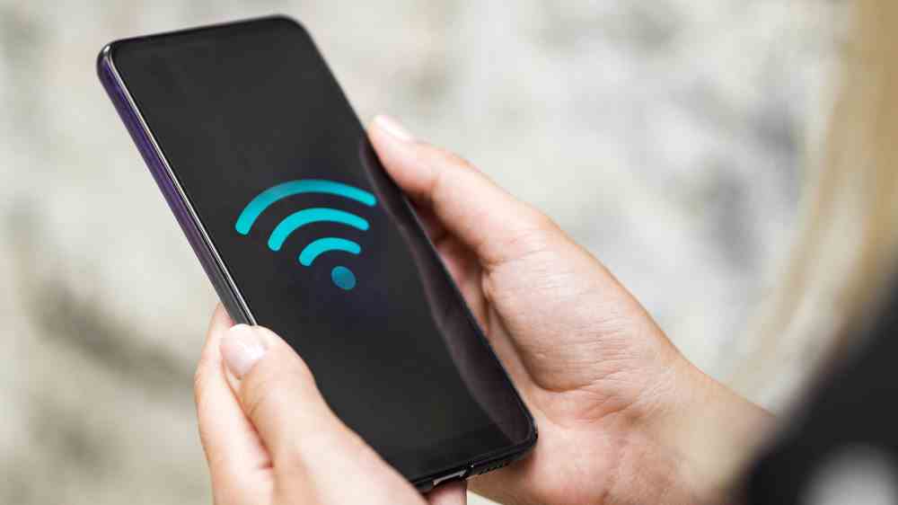 Le symbole Wi-Fi affiché sur l'écran d'un smartphone tenu dans les mains d'une personne.