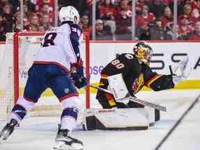 Le gardien de but des Flames de Calgary Daniel Vladar effectue un arrêt contre l'attaquant des Blue Jackets de Columbus Boone Jenner au Scotiabank Saddledome de Calgary le lundi 23 janvier 2023.