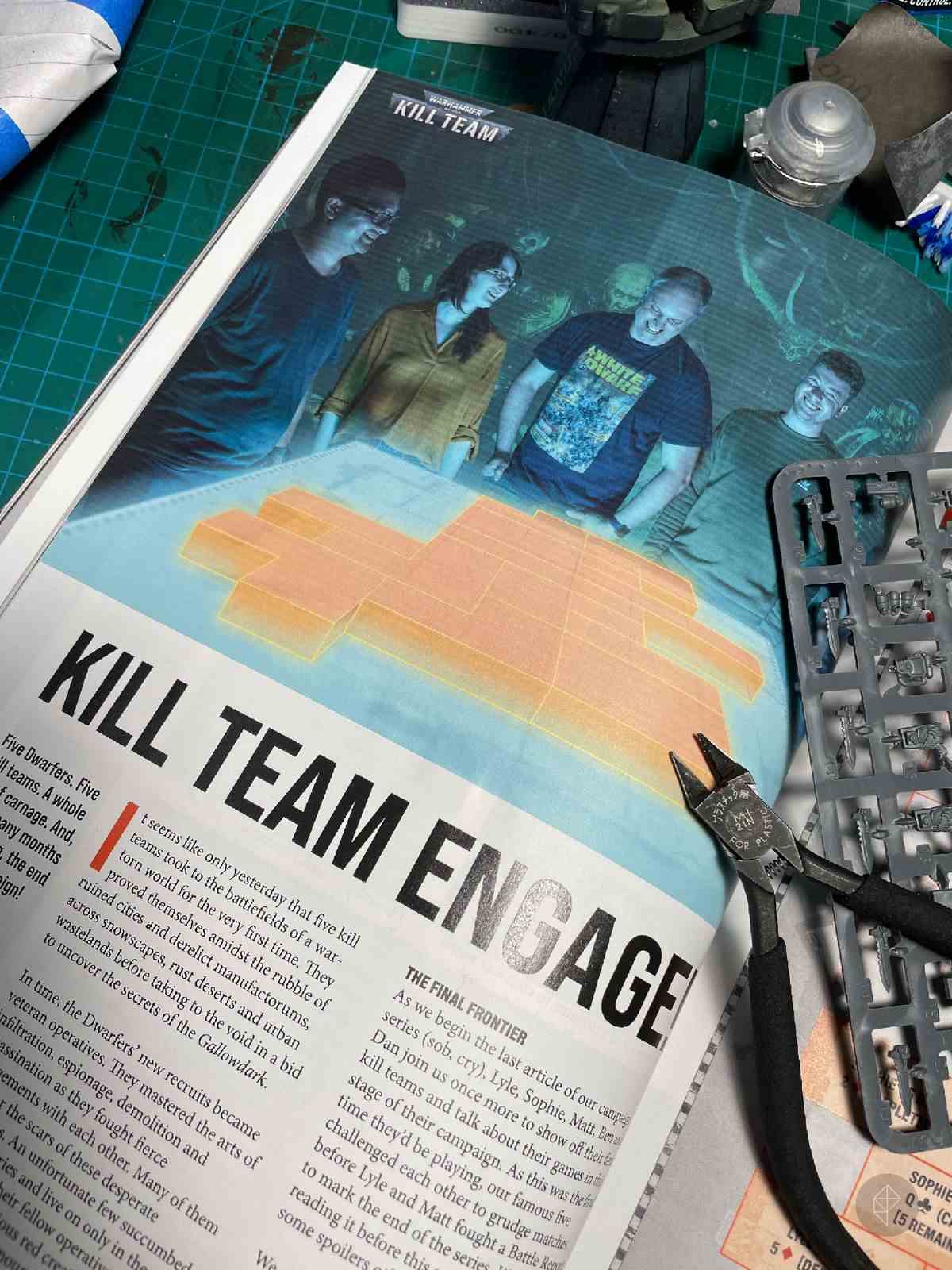 Une page de White Dwarf montrant un groupe de joueurs autour d'une carte virtuelle Kill Team.