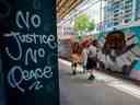 Des gens marchent devant une murale de George Floyd dans Graffiti Alley au centre-ville de Toronto, le 11 juin 2020. La ruelle bien connue de Toronto a été peinte avec des personnalités noires éminentes et des messages de solidarité contre le racisme anti-noir. 