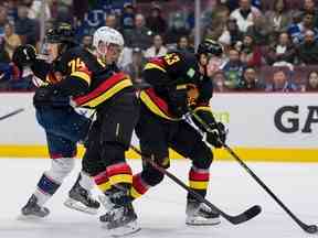 Le défenseur des Canucks de Vancouver Ethan Bear (74) vérifie l'attaquant des Blue Jackets de Columbus Patrik Laine (29) alors que le défenseur Quinn Hughes (43) récupère la rondelle libre en deuxième période au Rogers Arena le 27 janvier 2023.