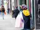 Une femme portant un masque et des gants porte un sac à provisions lors d'une réouverture progressive des restrictions sur les coronavirus à Toronto le 19 mai 2020.