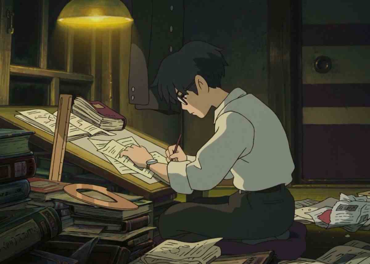 Jiro travaillant à son bureau de dessin éclairé par une lumière en surplomb dans The Wind Rises