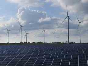 Des éoliennes tournent derrière un parc d'énergie solaire près de Prenzlau, en Allemagne.