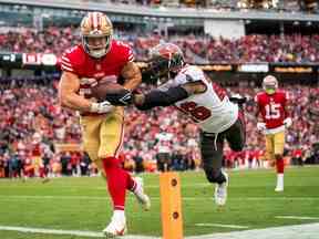 Le porteur de ballon des 49ers Christian McCaffrey (23 ans) marque un touché contre la sécurité des Buccaneers de Tampa Bay, Logan Ryan, dimanche.