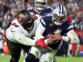 Le quart-arrière des Dallas Cowboys Dak Prescott, à droite, précipite le ballon pour un touché contre l'ailier défensif des Buccaneers de Tampa Bay Akiem Hicks en première mi-temps lors du match de wild card au Raymond James Stadium de Tampa, en Floride, le 16 janvier 2023.