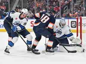 L'ailier gauche des Oilers d'Edmonton Zach Hyman (18 ans) tire sur le gardien des Jets de Winnipeg Connor Hellebuyck (37 ans) et le défenseur Dylan Samberg (54 ans) lors de la première période à Rogers Place à Edmonton le samedi 31 décembre 2022.