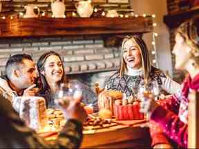 Des personnes de la génération Y dégustant des bonbons de Noël à la maison - Concept de réveillon du Nouvel An et de vacances d'hiver avec de jeunes amis s'amusant à manger ensemble le soir - Filtre chaud de guirlandes lumineuses