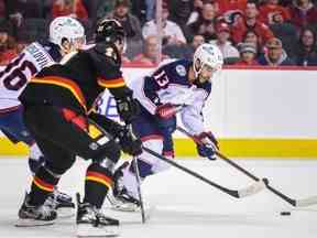 L'attaquant des Blue Jackets de Columbus Johnny Gaudreau contre l'attaquant des Flames de Calgary Mikael Backlund poursuit la rondelle au Scotiabank Saddledome à Calgary le lundi 23 janvier 2023