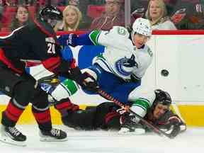 Le défenseur des Canucks de Vancouver Ethan Bear (74) vérifie le centre des Hurricanes de la Caroline Seth Jarvis (24) au cours de la première période au PNC Arena.