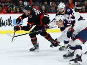 L'ailier gauche des Sénateurs d'Ottawa Brady Tkachuk tire alors que le défenseur des Blue Jackets de Columbus Erik Gudbranson (44 ans) et le défenseur Gavin Bayreuther (15 ans) défendent lors de la première période de la LNH au Centre Canadian Tire le mardi 3 janvier 2023.