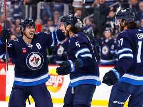 Le défenseur des Winnipeg Jets Brenden Dillon (5) célèbre son but en deuxième période avec le centre Mark Scheifele (55) et le centre Adam Lowry (17) contre les Flames de Calgary au Canada Life Centre à Winnipeg le mardi 3 janvier 2023.