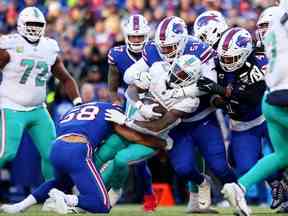 Matt Milano # 58 et Eli Ankou # 51 des Bills de Buffalo s'attaquent à Jeff Wilson Jr. # 23 des Dolphins de Miami pendant la seconde moitié du match lors du match éliminatoire de l'AFC wild card au Highmark Stadium le 15 janvier 2023 à Orchard Park, New York.