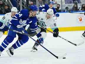 L'attaquant des Maple Leafs de Toronto Auston Matthews porte la rondelle devant l'attaquant du Seattle Kraken Jared McCann au cours de la deuxième période à la Scotiabank Arena.