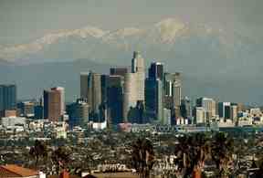 Dans cette photo d'archive du 31 décembre 2014, la ligne d'horizon de la ville de Los Angeles se dresse devant les montagnes enneigées de San Gabriel après qu'une tempête de neige a frappé la région.