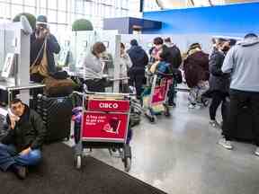 Un passager confronté à des retards et à des annulations téléphone aux compagnies aériennes à l'aéroport international Pearson de Toronto le 23 décembre 2022.