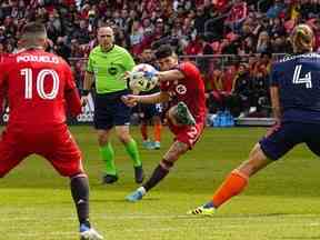 Le milieu de terrain du Toronto FC Jonathan Osorio lance le ballon entre le milieu de terrain Alejandro Pozuelo et le défenseur du FC Cincinnati Nick Hagglund au cours de la première moitié au BMO Field.