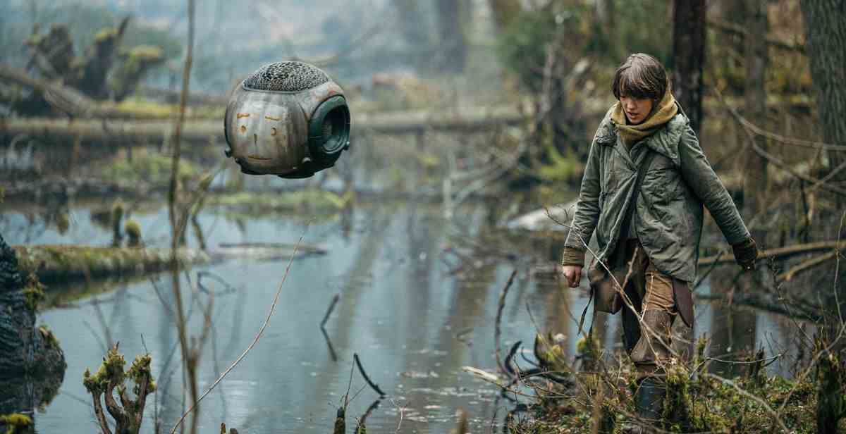 Raffiella Chapman se promène dans le gazon marécageux d'une Terre post-apocalyptique, avec un compagnon robot flottant, dans Vesper