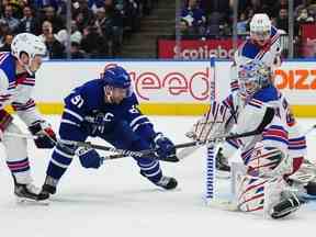 Le gardien de but des Rangers de New York Igor Shesterkin effectue un arrêt sur John Tavares des Maple Leafs alors que Ryan Lindgren des Rangers défend au cours de la deuxième période à Toronto le mercredi 25 janvier 2023.