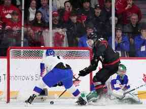 Connor Bedard, au centre, du Canada, marque le but vainqueur devant le gardien slovaque Adam Gajan à droite et Simon Nemec pendant la prolongation du quart de finale du Championnat mondial de hockey junior de l'IIHF à Halifax, le lundi 2 janvier 2023.