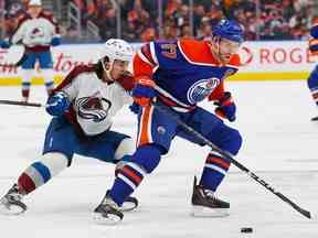 L'attaquant des Oilers d'Edmonton Connor McDavid (97) protège la rondelle contre l'attaquant de l'Avalanche du Colorado Alex Newhook (18) au cours de la deuxième période à Rogers Place.