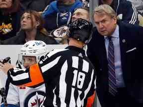 L'entraîneur-chef des Jets de Winnipeg, Rick Bowness (à droite), écoute l'arbitre Tom Chmielewski (18 ans) lors de la deuxième période contre les Penguins de Pittsburgh au PPG Paints Arena de Pittsburgh, le vendredi 13 janvier 2023.