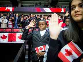 De nouveaux Canadiens prêtent serment lors d'une cérémonie spéciale de citoyenneté tenue à Ottawa avant un match de hockey entre les Sénateurs d'Ottawa et les Flames de Calgary.  Le Canada a récemment annoncé qu'il augmenterait ses objectifs annuels en matière d'immigration.