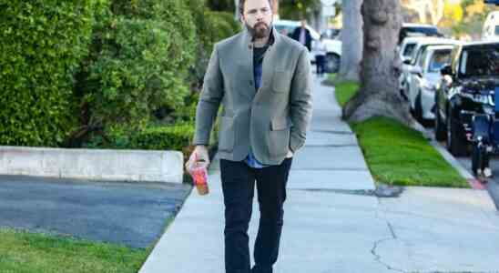 Ben Affleck walking down the street, holding a Dunkin Donuts coffee.