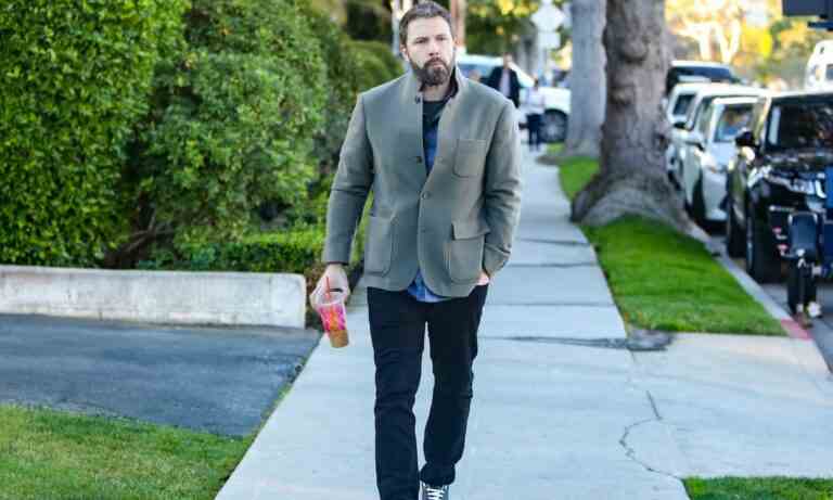 Ben Affleck walking down the street, holding a Dunkin Donuts coffee.