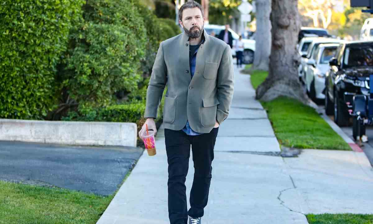 Ben Affleck walking down the street, holding a Dunkin Donuts coffee.