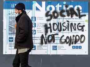 Un piéton passe devant des graffitis indiquant « Social Housing Not Condo » au centre-ville de Toronto.  La demande de logements au Canada est plus forte que ne le suggèrent les estimations officielles, soutient un économiste.