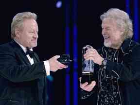 Randy Bachman détient le Juno alors que Robbie Bachman filme un gros plan du trophée après avoir été intronisé au Panthéon de la musique canadienne lors des Juno Awards à Winnipeg, le 30 mars 2014.