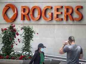 Des gens passent devant l'immeuble de Rogers Communications Inc. à Toronto.