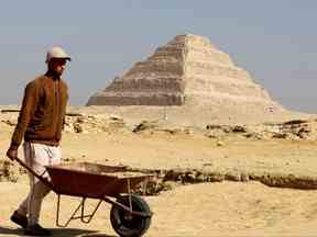 Un ouvrier marche devant la pyramide de Djoser après l'annonce de la découverte de tombes scellées vieilles de 4 300 ans à Gizeh, en Égypte, le 26 janvier 2023.